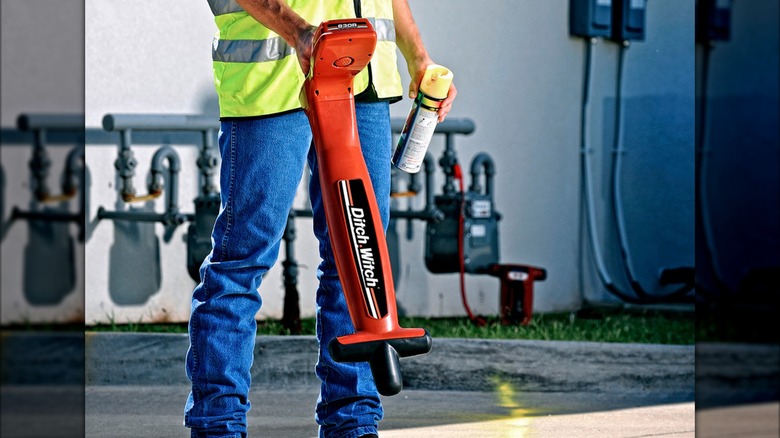 A man using a Ditch Witch utility locator to find underground lines and marking them with spray paint in Perry, Oklahoma.