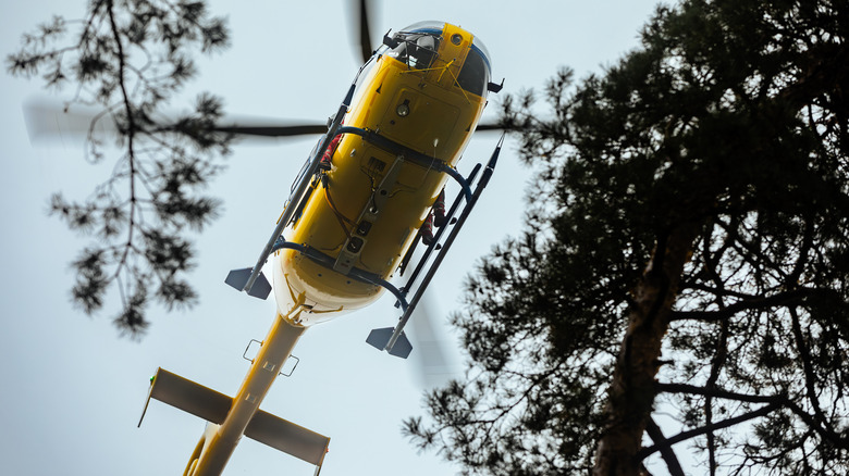 Low angle view of a yellow flying emergency medical service helicopter