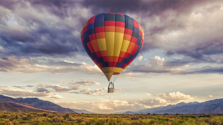 A hot air balloon flying over a field.