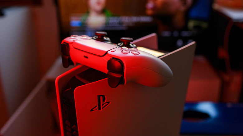 An upright PlayStation 5 with a controller balanced on it.