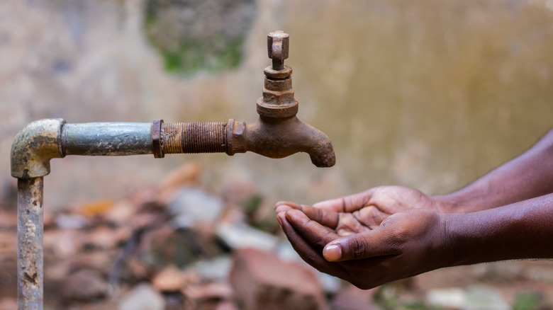 Man placing hand below dried tap.