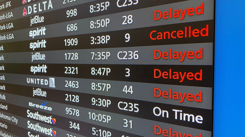 An airport flight board showing delayed and cancelled flights.