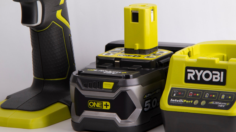 A close-up of a Ryobi One+ battery alongside a drill and charger