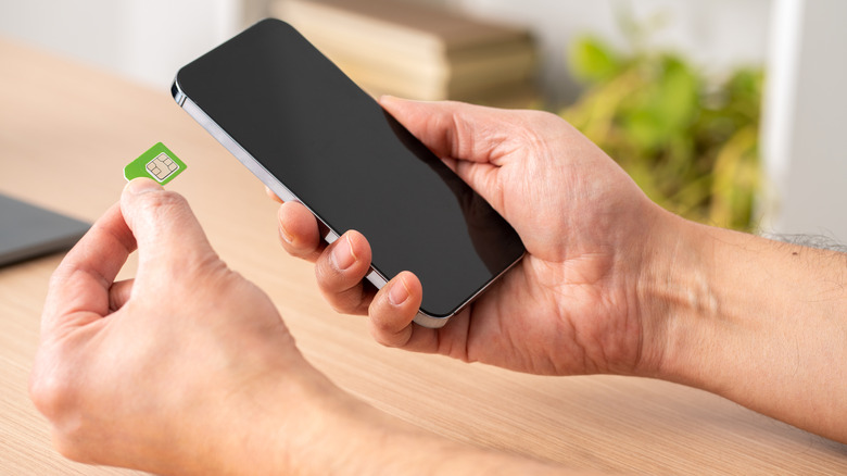 Hands holding a smartphone and inserting a SIM card