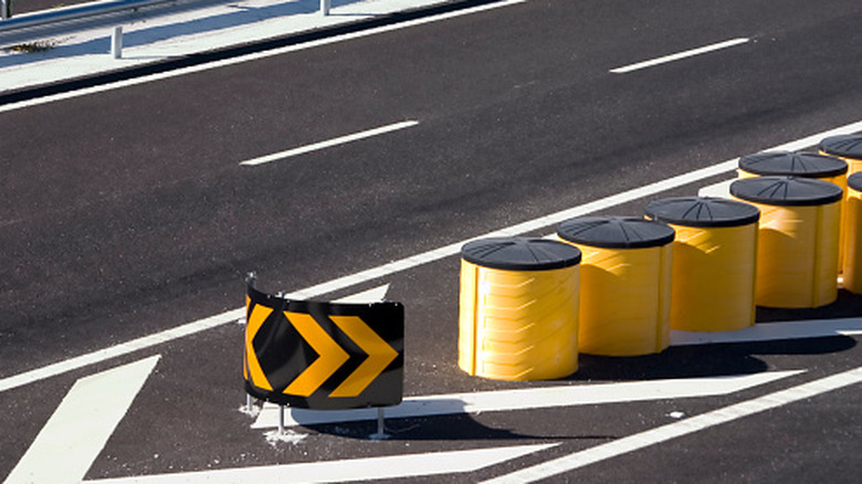 Overhead view of yellow crash barrels at a highway junction.