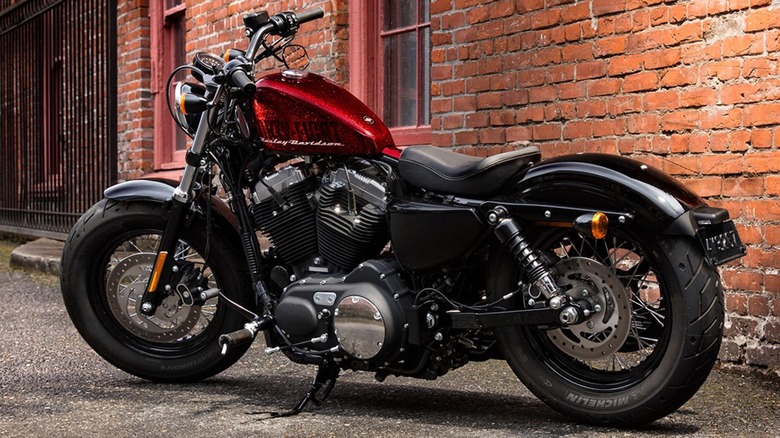 A red Harley-Davidson with Michelin tires in front of a red brick building