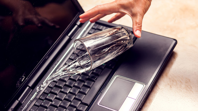 Glass of water falling on laptop