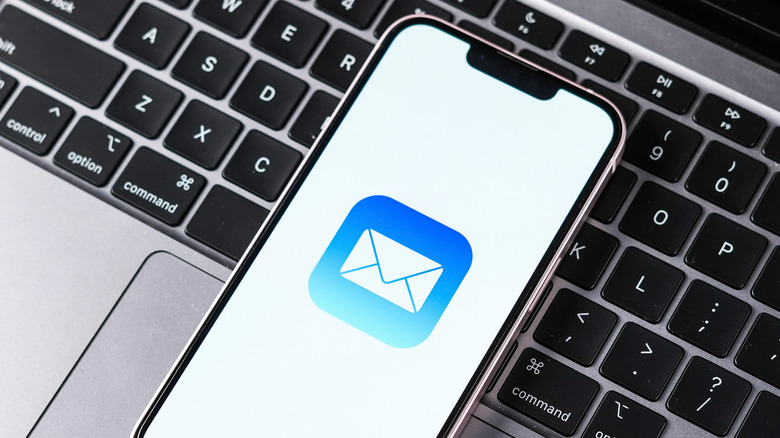 iPhone on a MacBook keyboard showing Mail app icon