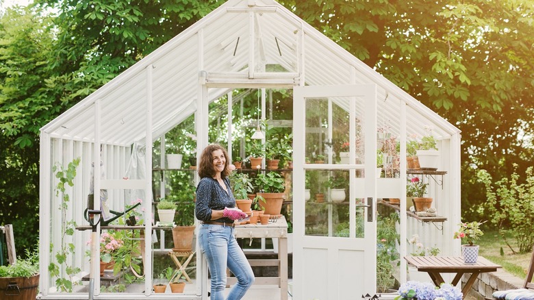 Woman standing in front of backyard greenhouse
