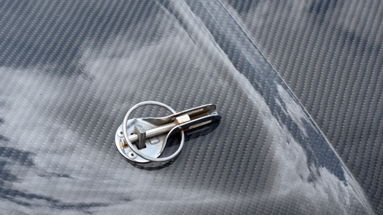 A close-up of a carbon fiber hood with a traditional hood pin.