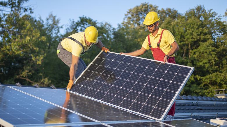 men installing solar panels on roof