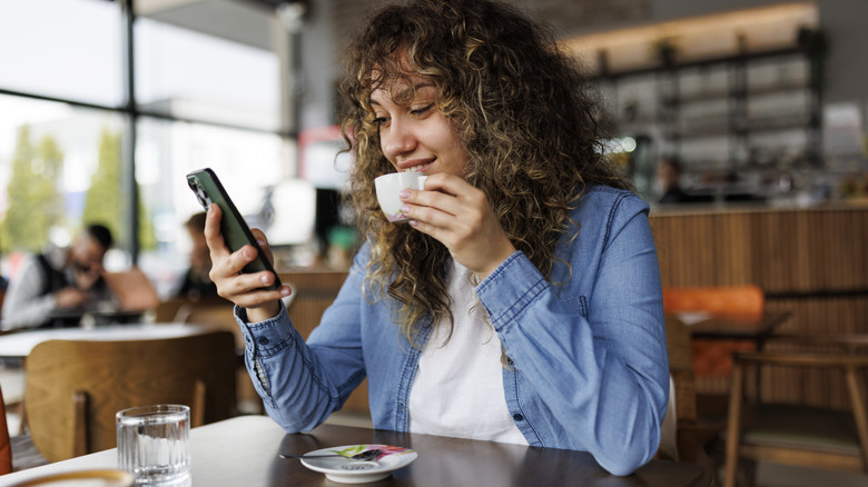 Woman using phone in cafe