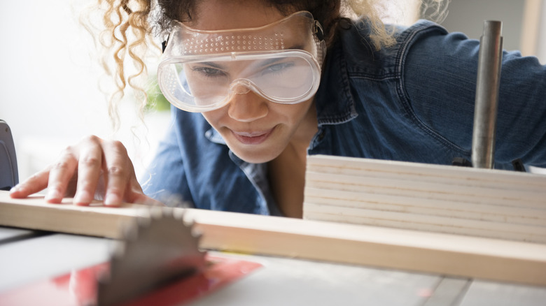 Woman lining up wood to saw blade