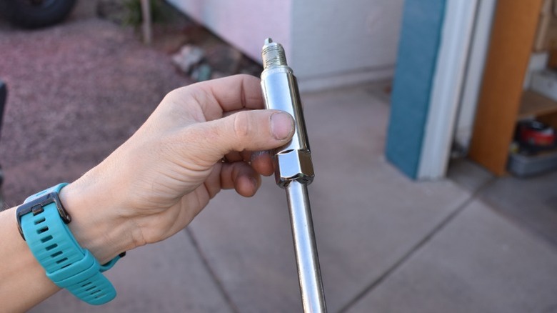 A person holding a spark plug socket attached to an extension with a spark plug inside