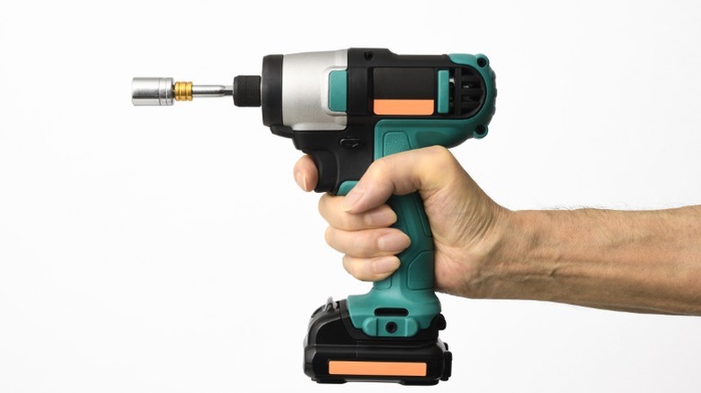 A person holding an impact driver with a socket attachment