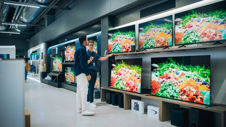 Person showing televisions to a customer in a store