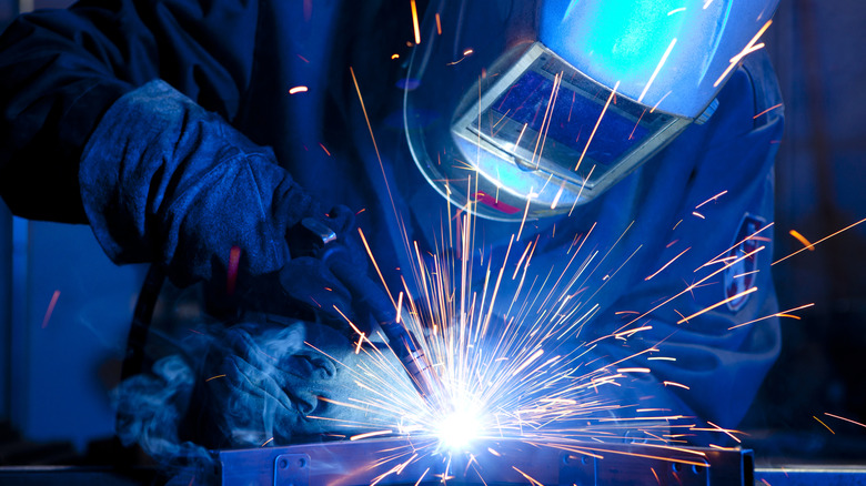 Welder welding and wearing welding helmet.