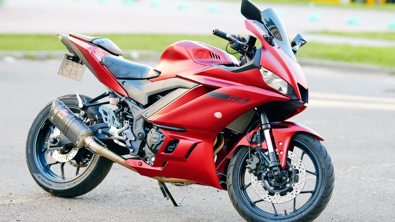 . Sleek red Yamaha YZF R3 parked in city parking lot, modern sports motorcycles