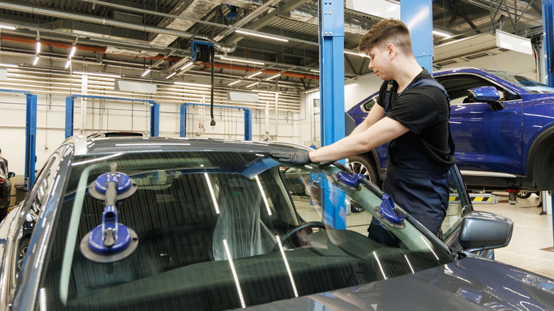 A mechanic repairs a broken windshield at a car repair shop