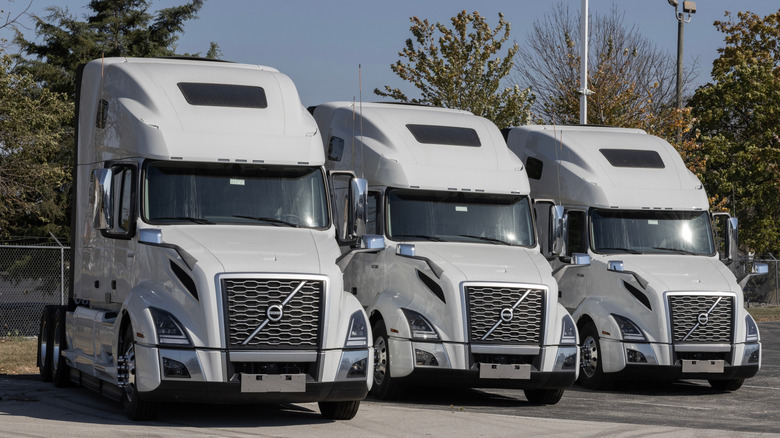 Three white Volvo VNL760 trucks parked side-by-side