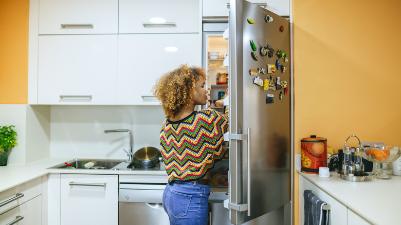 Person standing in front of an opened refrigerator