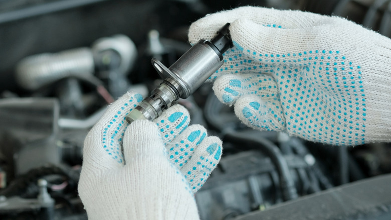 A new VVT-I valve is in the hands of an auto mechanic.