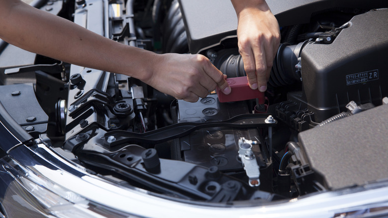 Human hand checking the engine of Toyota Altis showing the VVT-I engine