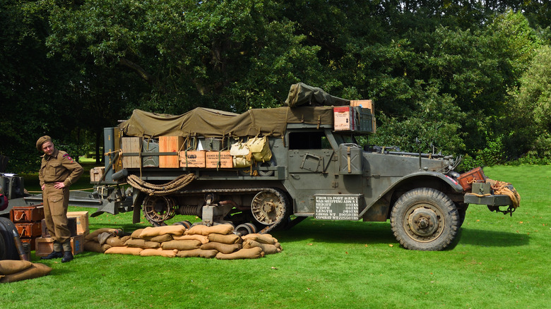 Vintage M3 Half Track with soldier standing to the left during a 2023 re-enactment