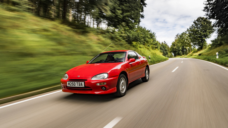 Front 3/4 view of a red Mazda MX-3 on the move