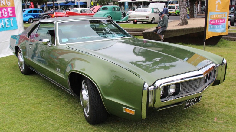 Green 1970 Oldsmobile Toronado parked on grass at a car show