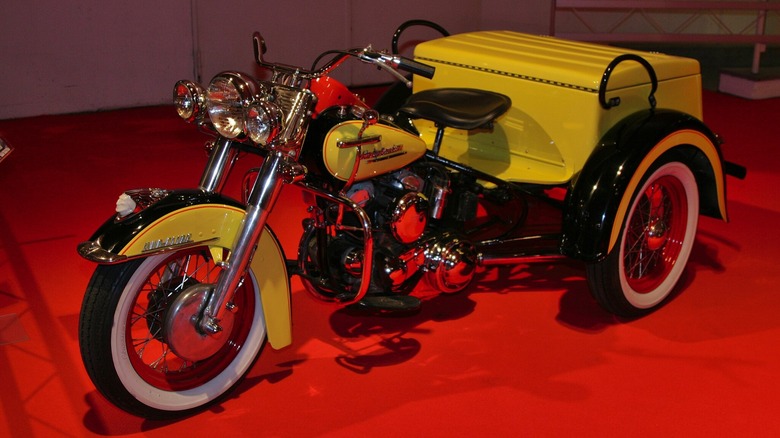 A yellow Harley-Davidson Servi-Car on display at a museum