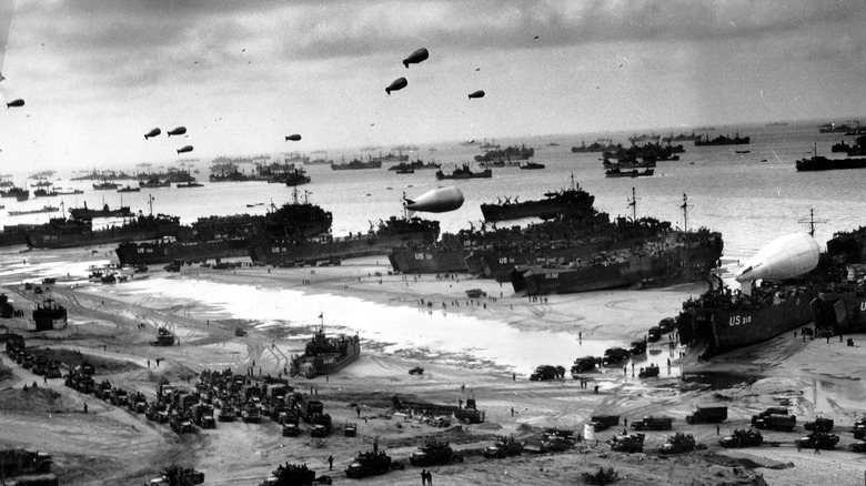 Ships putting cargo ashore on D-Day, with barrage balloons floating above