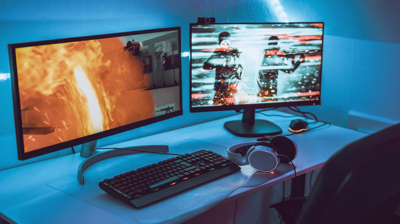 Two monitors on a desk with a keyboard and headphones