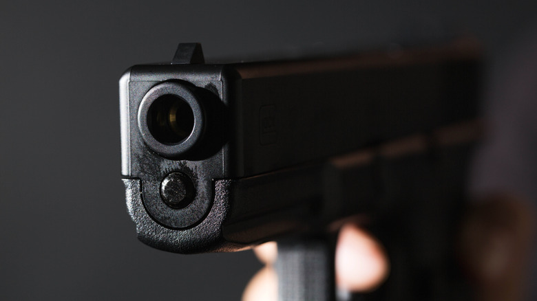 A closeup of a handgun barrel on a dark background