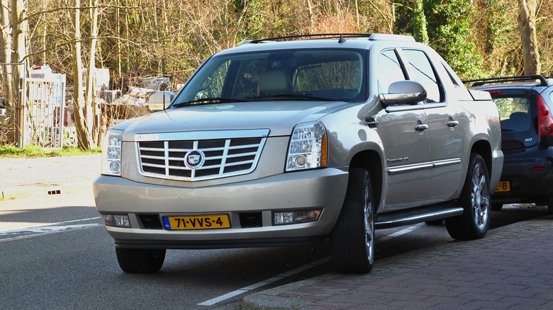 A gold Cadillac Escalade EXT parked on the street, front 3/4 view