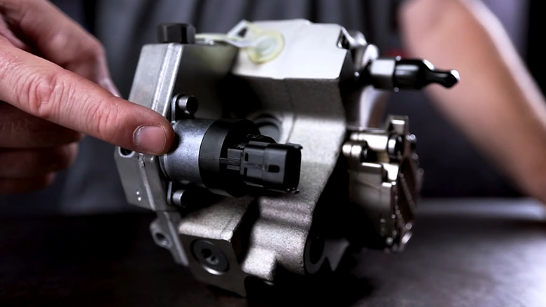 A finger pointing at the side of a CP3 fuel pump