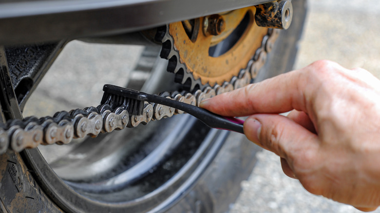 person cleaning motorcycle chain