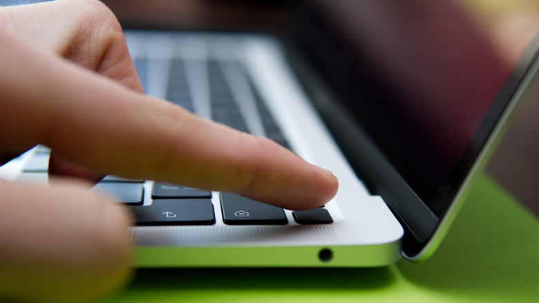 person pressing touch id MacBook