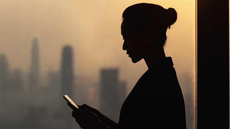Silhoutte of person using phone.