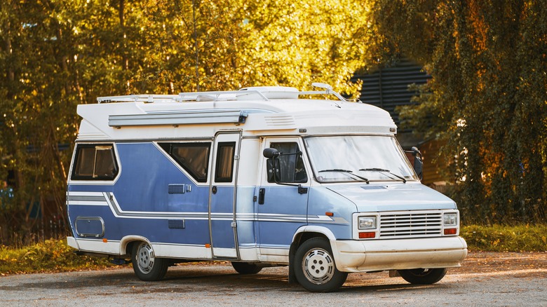 A classic motorhome, parked against trees