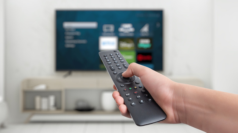 Hand holding remote control in front of TV