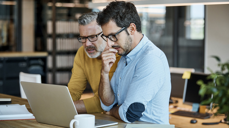 Two people using laptop at desk