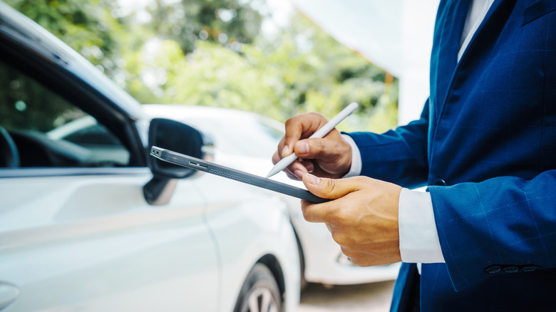 Insurance agent inspects a car