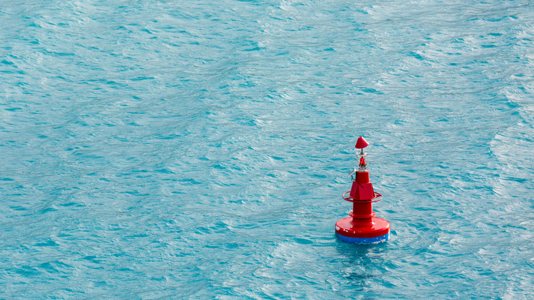 A red, solar powered ocean data relaying smart buoy afloat in the water