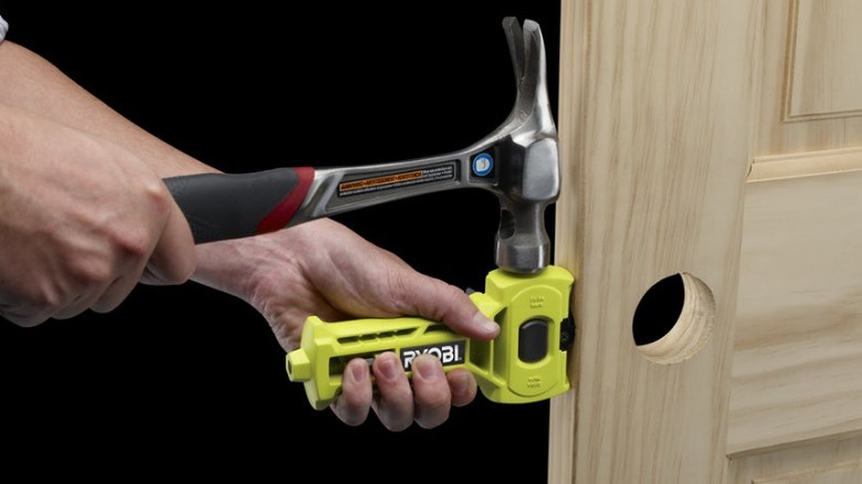 Person using Ryobi chisel attachment on door