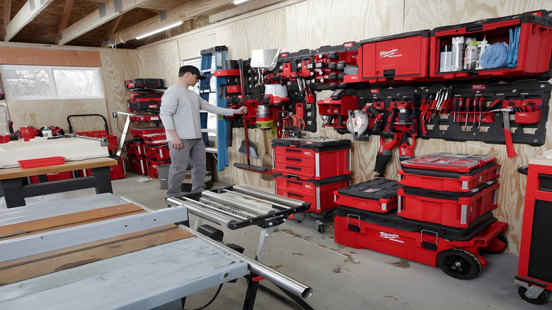 Man hanging broom in a garage full on Milwaukee tools