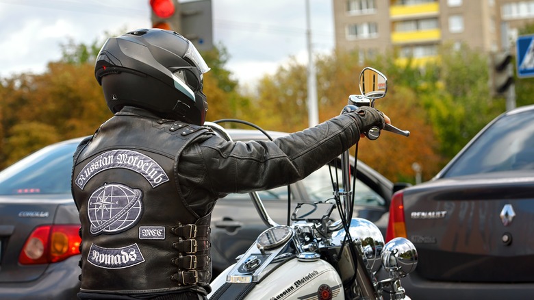Biker in full leather gear with Russian motoclub patches waiting at an intersection on Harley Davidson motorcycle.