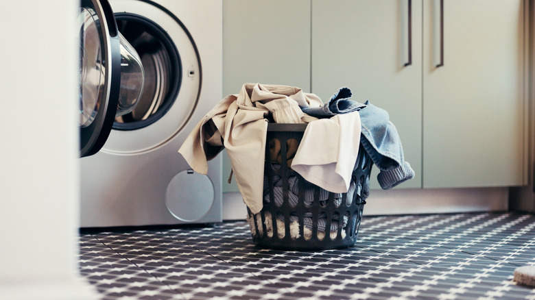 Unfolded laundry sitting in a basket by a clothes dryer