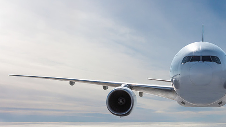 A white wide-body jet in the air, with one jet engine appearing on the right-hand wing
