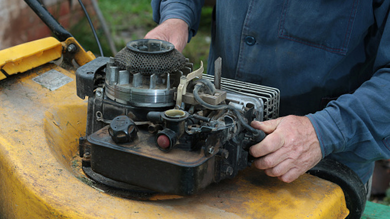 A man repairing a lawn mower engine